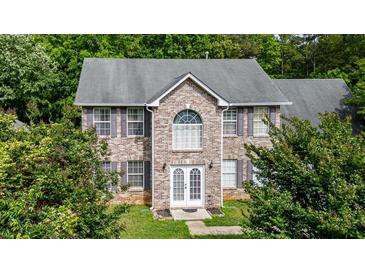 Two-story brick home featuring well-manicured landscaping, gray shutters, and a gabled entrance at 5857 Cobalt Dr, Powder Springs, GA 30127