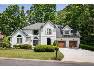 Elegant two-story home with a well-manicured lawn, two-car garage and traditional architectural details at 2912 Dunhill Trl, Woodstock, GA 30189