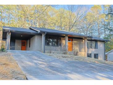 Well-maintained brick home with a covered carport, front porch, and a slightly sloping front yard at 4011 Lake Carlton Rd, Loganville, GA 30052