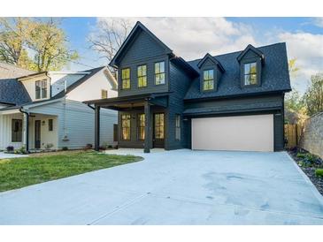 Charming two-story home boasts a dark blue exterior, dormer windows, and a spacious driveway at 2032 Spink Nw St, Atlanta, GA 30318