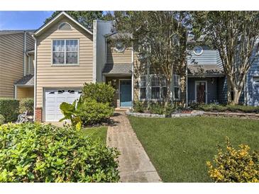 Charming townhome featuring a manicured lawn, blue door, and an attached one car garage at 3285 Long Iron Pl, Lawrenceville, GA 30044