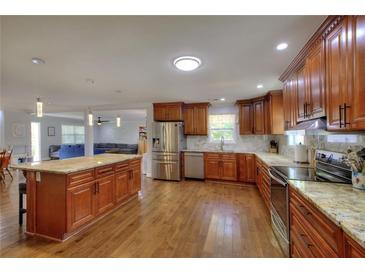 Open kitchen featuring wood cabinets, stainless steel appliances, and a large island with granite countertops at 2944 Berry Rd, Loganville, GA 30052