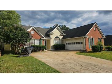 Charming brick and siding home featuring a two-car garage and a well-maintained front yard at 2860 Camelot Woods Dr, Lawrenceville, GA 30044