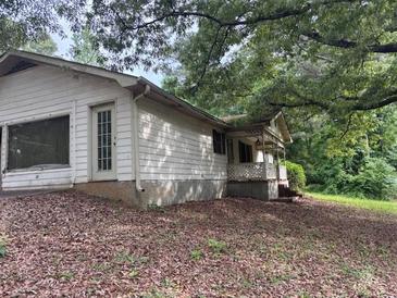 Exterior view of a ranch-style home with a covered porch and mature trees at 2368 Ebenezer Se Rd, Conyers, GA 30094