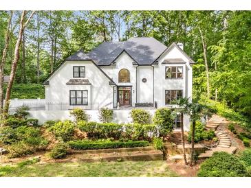 Stunning two-story white home with lush landscaping and a charming entrance, surrounded by mature trees at 900 Edgewater Nw Dr, Atlanta, GA 30328