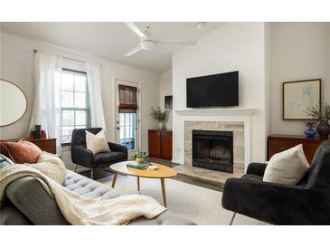Inviting living room featuring a cozy fireplace, plush seating, and a ceiling fan for added comfort at 448 Teal Ct, Roswell, GA 30076