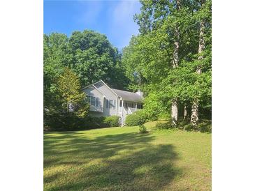 Traditional home with light siding, green lawn, and a beautiful surrounding landscape at 144 Wiley Dr, Douglasville, GA 30134