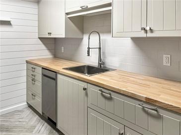 Updated kitchen with light gray cabinets, butcher block counters, stainless steel sink, and modern fixtures at 475 Mount Vernon Ne Hwy # 129C, Atlanta, GA 30328