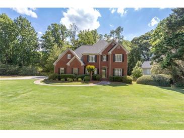 Beautiful two-story red brick home with a meticulously maintained lawn and mature landscaping at 3310 Chartwell Blvd, Suwanee, GA 30024