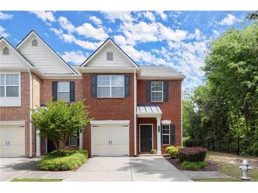 Charming brick townhome with a one-car garage, manicured lawn, and mature landscaping at 5686 Lawley Dr, Alpharetta, GA 30022