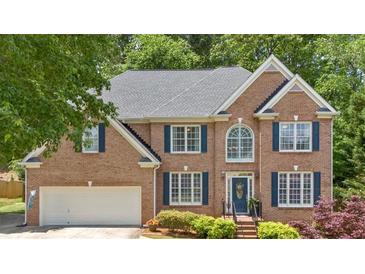 Charming brick home featuring a two-car garage, classic blue shutters, and beautifully manicured landscaping at 6034 Addington Nw Dr, Acworth, GA 30101