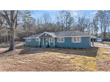 Charming single-story home features blue exterior paint, white trim, a landscaped yard and covered parking at 9588 Poston Rd, Jonesboro, GA 30238