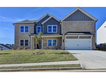 Inviting two-story home featuring a manicured lawn, attached two-car garage, and charming architectural details at 58 Longhorn Way, Auburn, GA 30011
