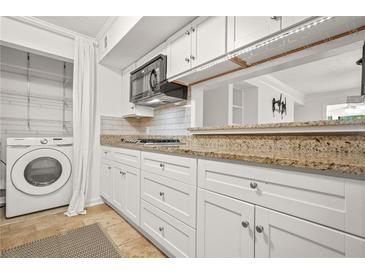 Bright kitchen featuring white cabinets, stainless steel appliances, and a convenient washer and dryer at 228 Smokerise Se Cir, Marietta, GA 30067