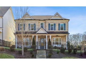 Charming two-story brick home features a manicured front yard, a wrought iron fence and a covered front porch at 3332 Old Concord Se Rd, Smyrna, GA 30082