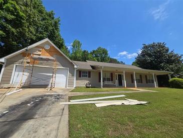 Charming ranch home with a covered front porch and a spacious front yard under a sunny sky at 65 King James Se Ct, Conyers, GA 30013