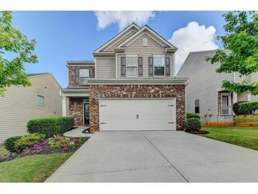 Charming two-story home featuring a brick facade, large two car garage, and a well manicured front lawn at 1345 Aster Ives Dr, Lawrenceville, GA 30045