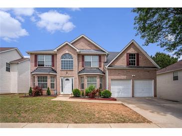 Charming two-story brick home features a two-car garage and manicured front yard, perfect for curb appeal at 3740 Arminto Dr, Ellenwood, GA 30294