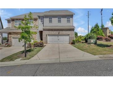 Two-story townhome showcasing a two-car garage and a well-maintained front yard and driveway at 1610 Habersham Villa Dr, Cumming, GA 30041
