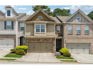 Beautiful townhouse showcasing a stone front, a two-car garage, and manicured landscaping enhancing its curb appeal at 3040 Clear View Ln, Snellville, GA 30078