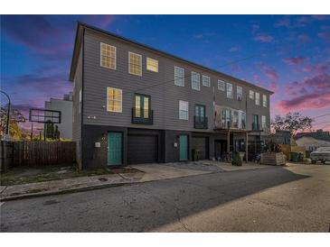 Three-story townhome with gray siding, black brick foundation, and brightly colored doors at 93 Terry St # A, Atlanta, GA 30312
