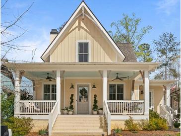 Charming yellow two-story home with inviting front porch, white columns, and brick-lined steps at 11190 Serenbe Ln, Chattahoochee Hills, GA 30268