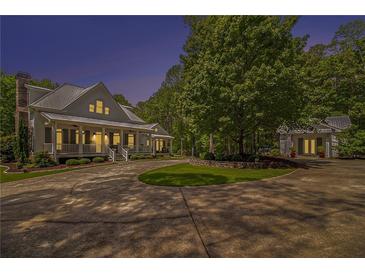 Inviting covered porch with comfortable seating, a ceiling fan, and stone steps amidst lush landscaping at 8901 Watkins Mill Rd, Winston, GA 30187