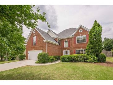 Charming two-story brick home featuring a well-manicured lawn, attached garage, and decorative red shutters at 1130 Laurel Cove Dr, Snellville, GA 30078