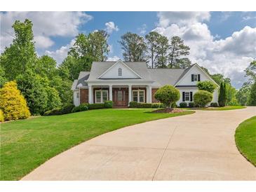 Charming home with a manicured lawn and a circular driveway, lush landscaping, and inviting entryway at 100 Ashley Hall Ct, Woodstock, GA 30188