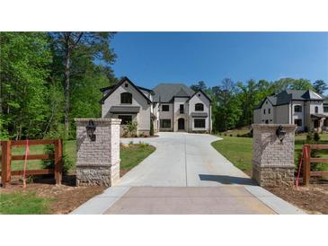 Elegant home with a private driveway, stone accents, manicured lawn and lush landscaping at 10765 Shallowford Rd, Roswell, GA 30075