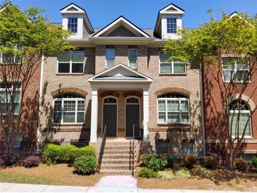 Charming townhome featuring a brick facade, dormer windows and landscaped front yard at 10856 Ellicot Way, Alpharetta, GA 30022
