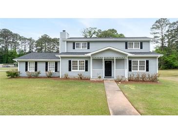 Charming two-story home with a cozy front porch and a well-maintained lawn and manicured shrubs at 100 Fairview Dr, Stockbridge, GA 30281
