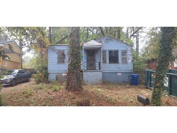 Exterior view of a blue home with bars on the windows, surrounded by trees at 1182 Bronx Nw St, Atlanta, GA 30314