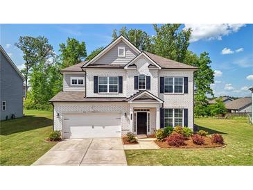 Charming two-story home with a white brick facade, attached garage, manicured lawn, and beautiful landscaping at 7455 Easton Valley Ln, Cumming, GA 30028