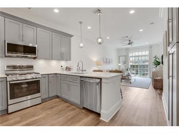 Open kitchen featuring stainless steel appliances, light gray cabinetry, and an island with quartz countertop at 1055 Piedmont Ne Ave # 409, Atlanta, GA 30309