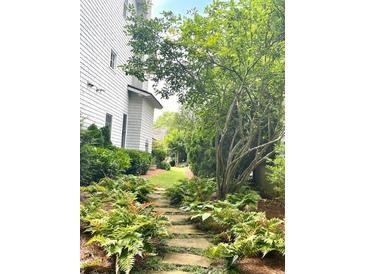 Stone pathway through lush backyard garden, leading to well-manicured lawn and landscaping at 6575 Eli Davis Rd, Cumming, GA 30040