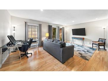 Inviting living room featuring hardwood floors, a gray sofa, balcony, and a sleek entertainment setup at 6851 Roswell Rd # H12, Atlanta, GA 30328