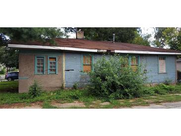 View of a neglected single-story home, showing peeling paint and overgrown bushes at 868 Oakhill Sw Ave, Atlanta, GA 30310