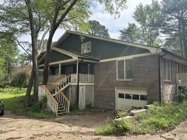Charming home featuring a brick facade, second-story porch, stairs, and two-car garage at 2256 Mack Rd, Douglasville, GA 30135