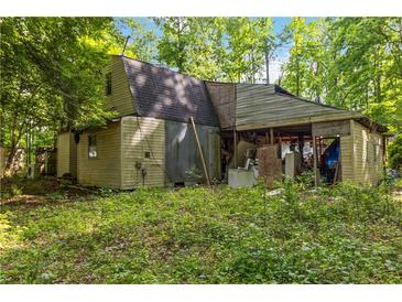 Rustic home exterior with tan siding, dark roof, and open-air structure at 4250 Deerfield Rd, Cumming, GA 30028