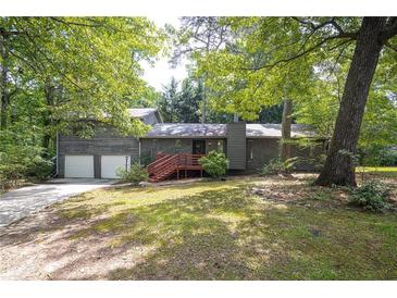 Charming gray home with a two-car garage, inviting red front deck and mature trees at 633 Iris Rd, Pine Lake, GA 30072