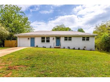 Charming single-story home with a metal roof, fresh white paint and vibrant blue doors and trim at 1755 Rockbridge Nw Rd, Conyers, GA 30012