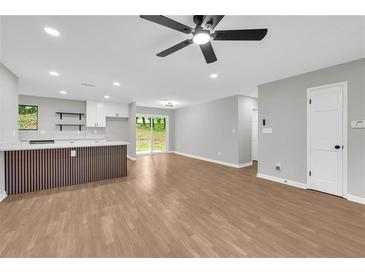 Bright living room with wood floors and white kitchen with breakfast bar in an open floorplan at 1829 Herringbone Holw, Lithonia, GA 30058