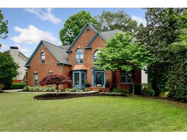 Charming two-story brick home featuring a well-manicured lawn and mature trees at 5010 Winding Hills Ln, Woodstock, GA 30189