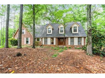 Charming brick home featuring a symmetrical facade, dormer windows, and lush surrounding greenery at 110 The Farm Rd, Mcdonough, GA 30252