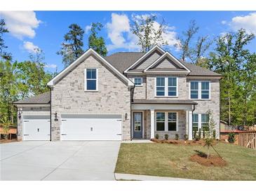 Stunning two-story home showcasing stone facade, manicured lawn, and a three car attached garage at 6944 Melody Ridge Rd, Buford, GA 30518