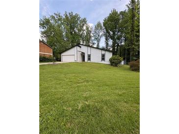 Exterior view of house with a green lawn and big trees in front of the property at 3285 Rollingbrook Way, Duluth, GA 30096
