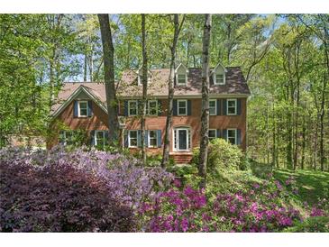 Charming brick home with a lush, landscaped front yard and colorful azaleas in a beautiful, wooded setting at 4152 Barberry Ne Dr, Roswell, GA 30075
