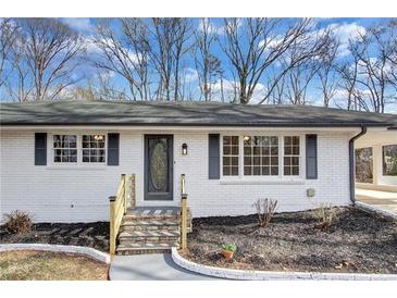 Charming single-story home with white brick, dark shutters, stone steps, and a well-manicured front yard at 5774 Forest Dr, Acworth, GA 30102