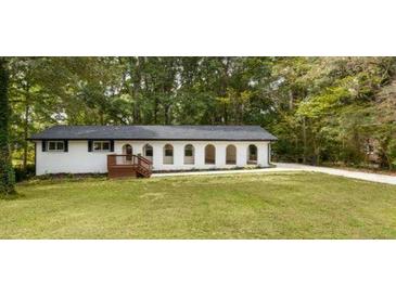 Charming single-story home featuring unique arched windows and a lush, expansive front lawn surrounded by mature trees at 1019 Crestwood Ln, Stone Mountain, GA 30087